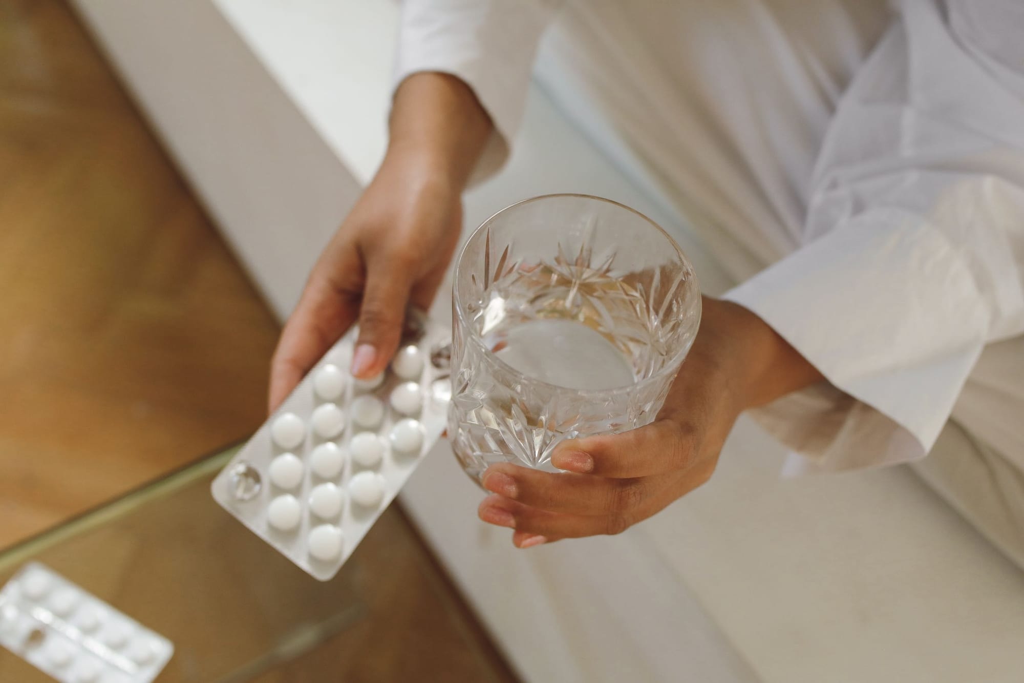 Kvinna som tar en tablett med ett glas vatten hemma