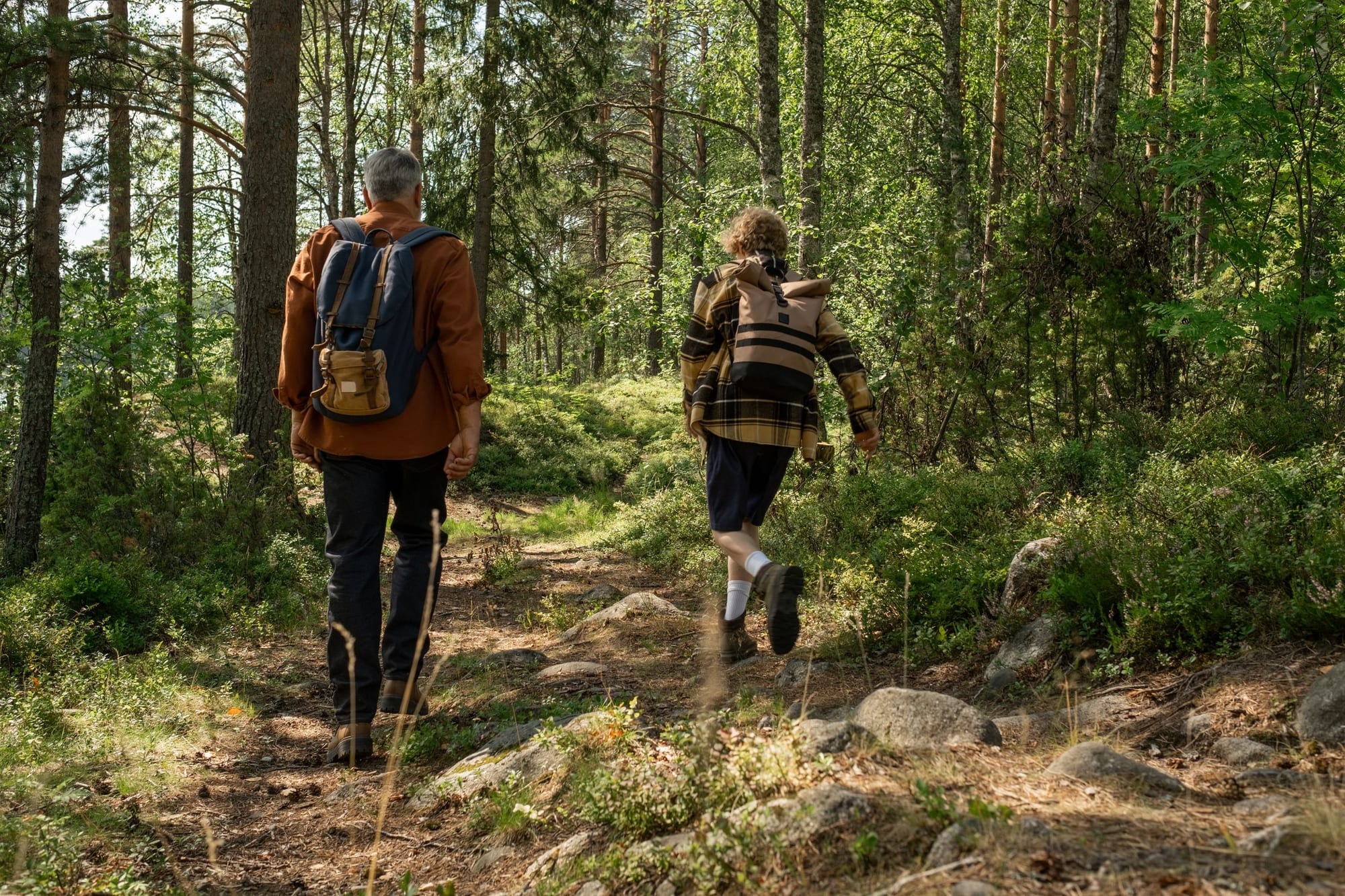 Två personer som vandrar på en skogsstig om sommaren