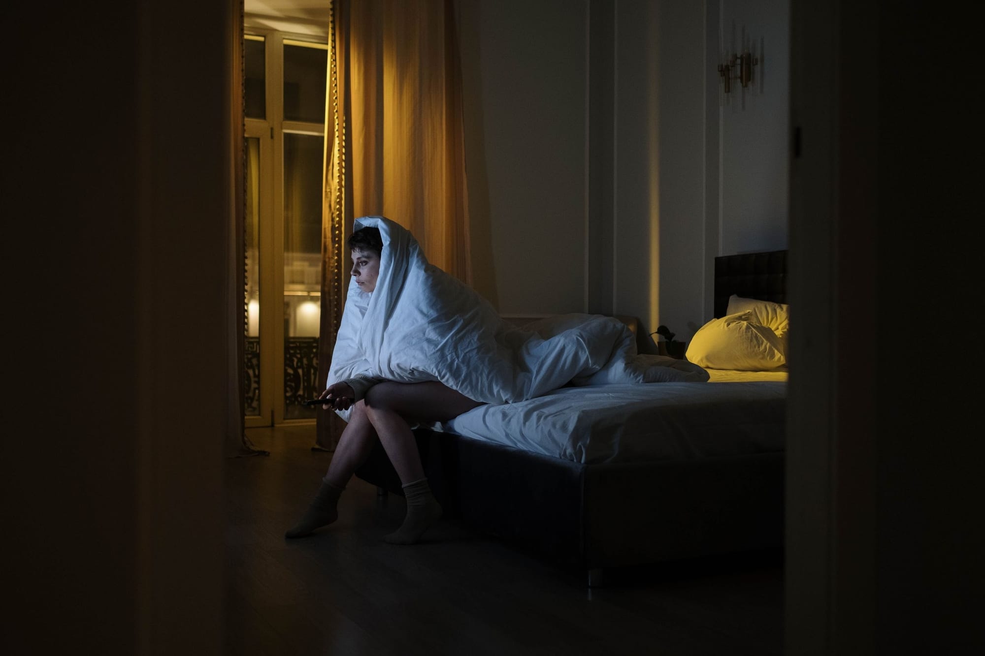 Person som ligger vaken i ett mörkt sovrum