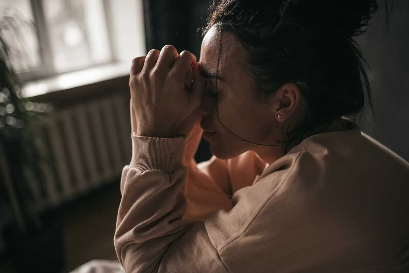 Kvinna med sömnproblem sitter trött och stressad – vad är REM-sömn och varför den är viktig för återhämtning via Doktera