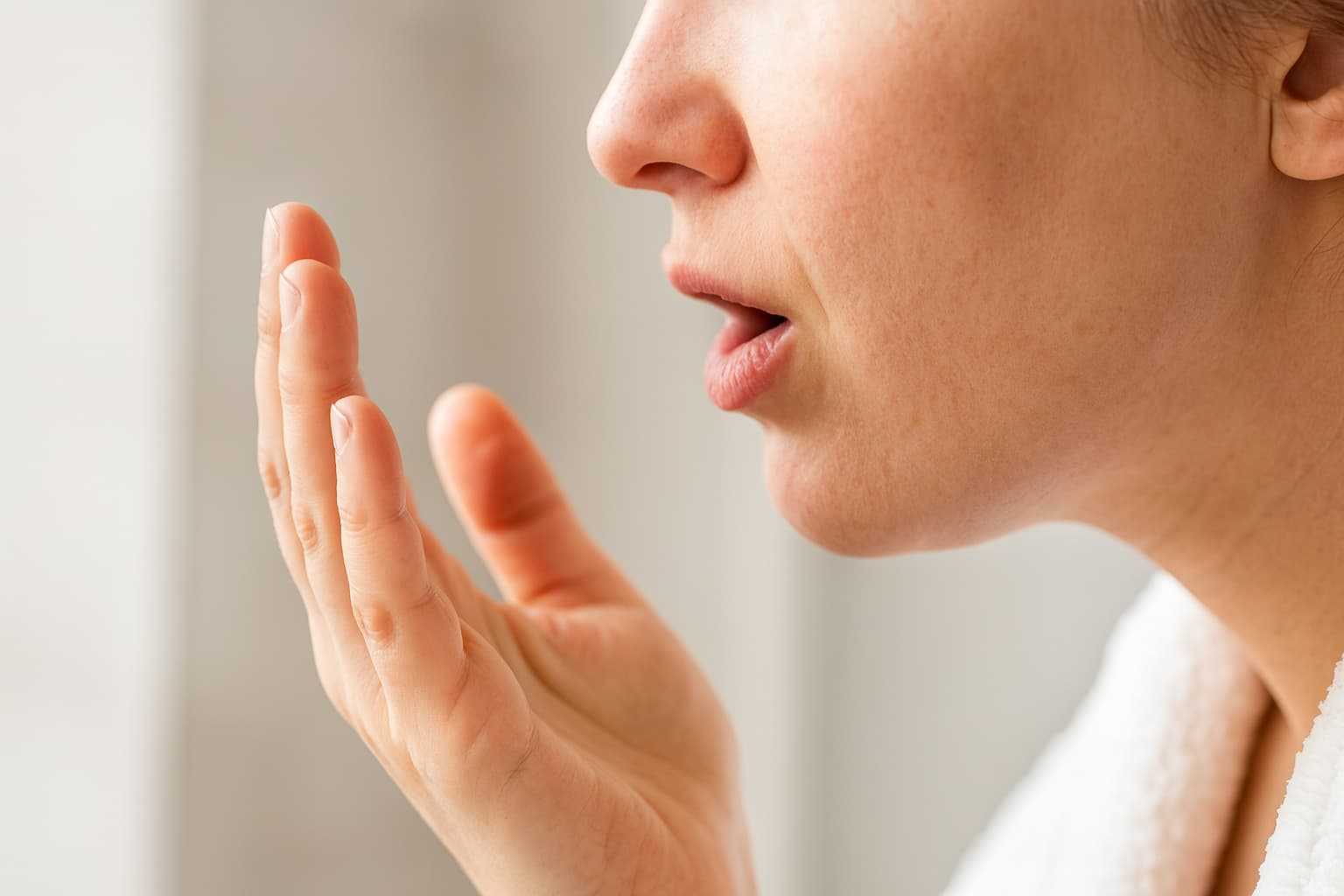 Person som kontrollerar sin andedräkt vid symtom på svamp i munnen och munsvamp – utredning och behandling via Doktera.