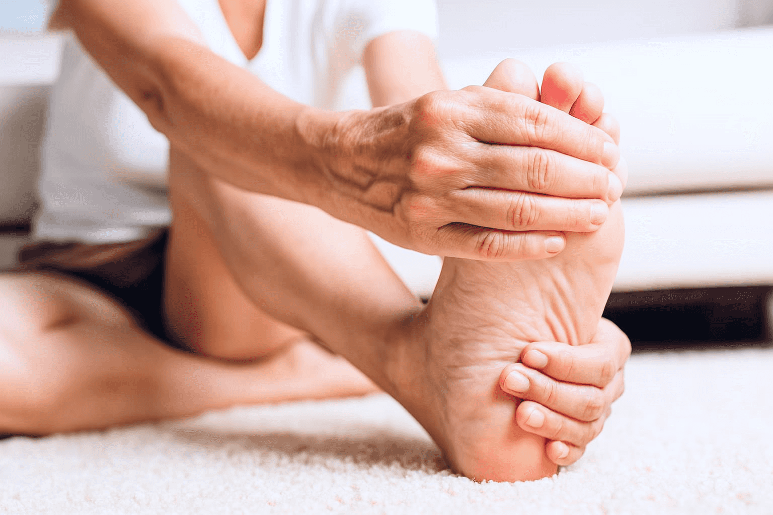 Person som håller om sin fot vid upplevda besvär av nagelsvamp – typiska symtom på svampinfektion i tånaglar. Bild för artikel om nagelsvamp på tår och fingrar hos Doktera.