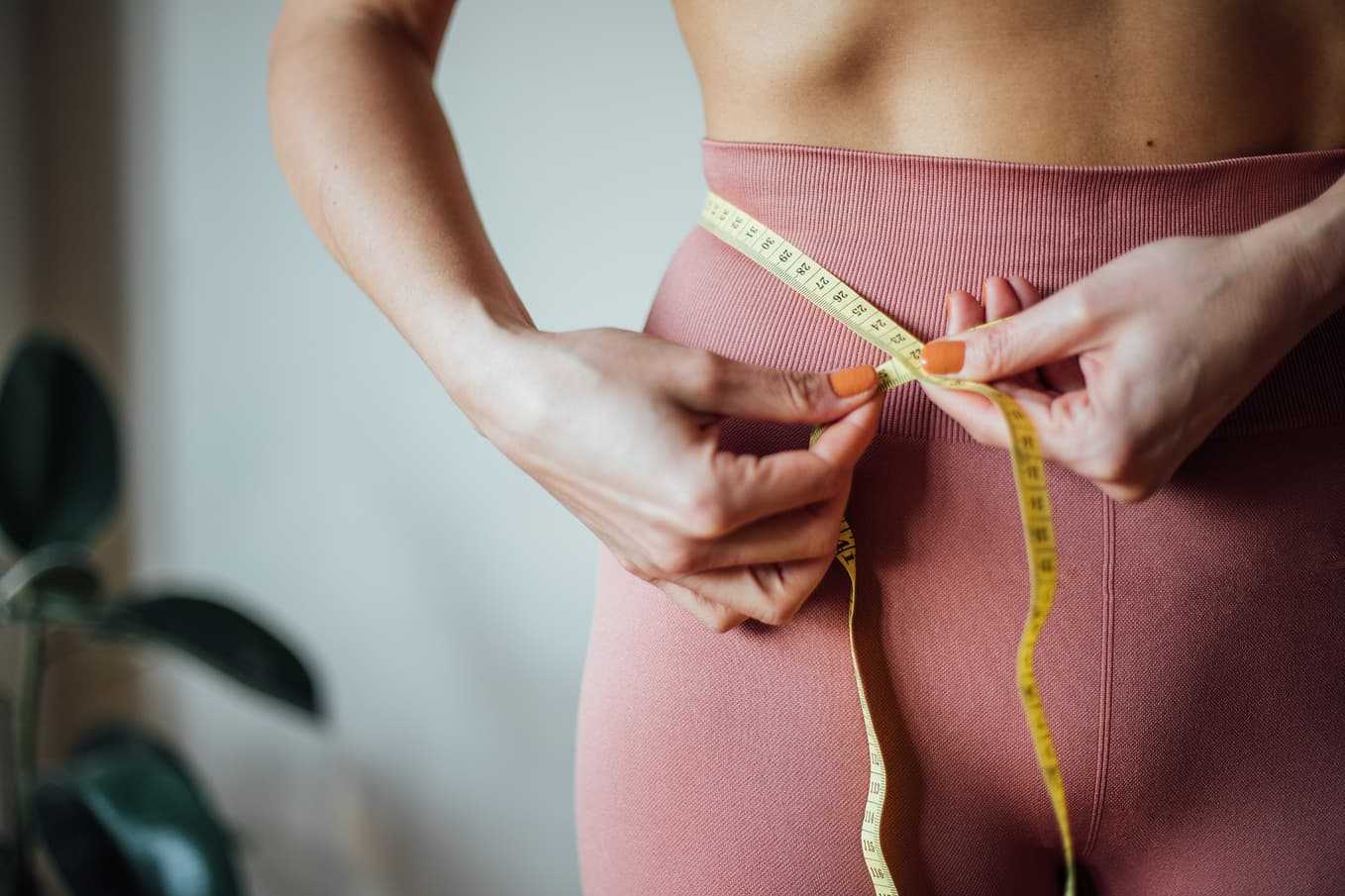 Kvinna mäter midjan med måttband – viktnedgång med diabetesmedicin som Ozempic, Rybelsus och Metformin via Doktera