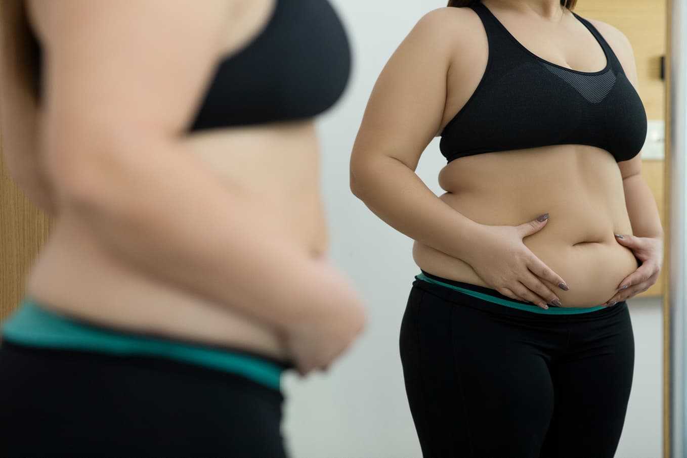 Kvinna med obesitas och fetma ser sig i spegeln – Doktera erbjuder medicinsk viktminskning online för dig som vill få hjälp snabbt och tryggt.
