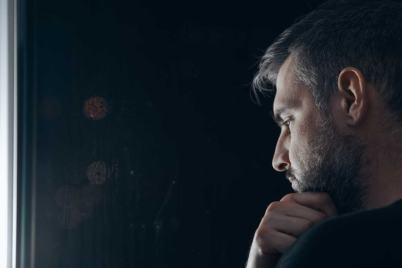 Äldre man ser fundersam ut vid fönster – artikel om erektionsproblem hos äldre, orsaker och hur man kan få hjälp och behandling hos Doktera.se